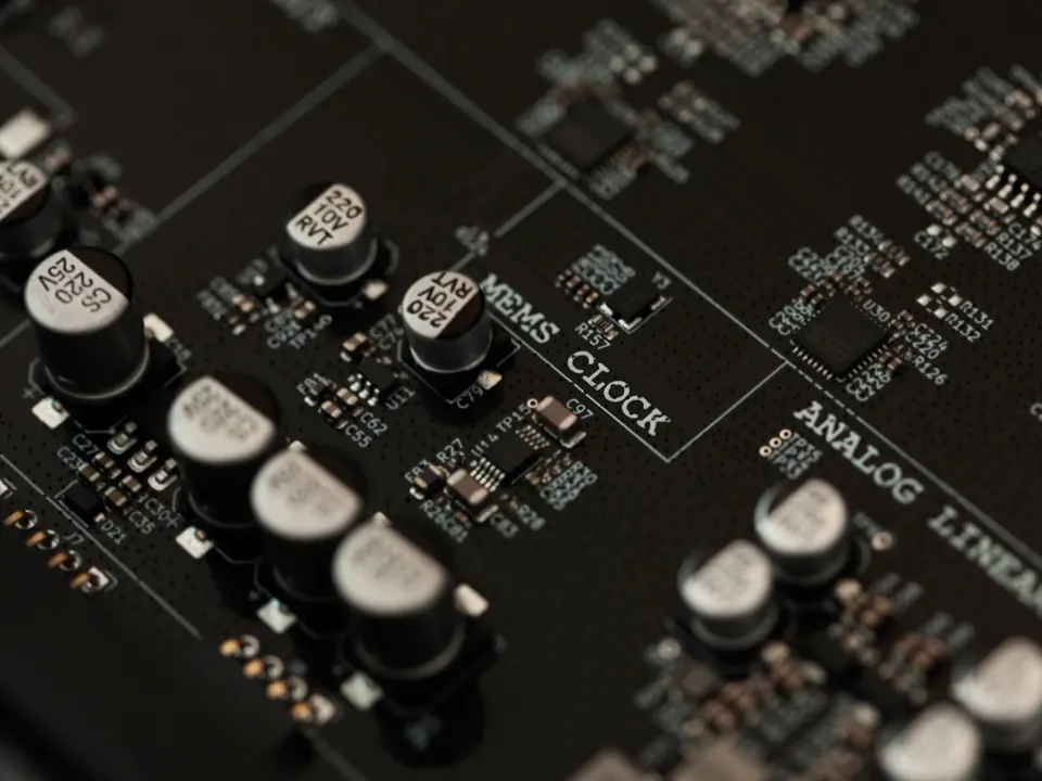 La scheda di Preciso vista di sbieco, con la scritta MEMS CLOCK stampata tra file di condensatori.
