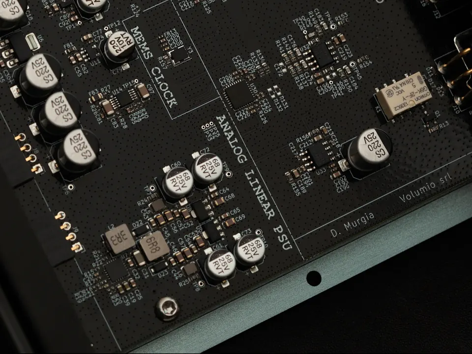 Un primo piano della scheda di Preciso, con le scritte MEMS CLOCK e ANALOG LINEAR PSU stampate tra condensatori e chip.